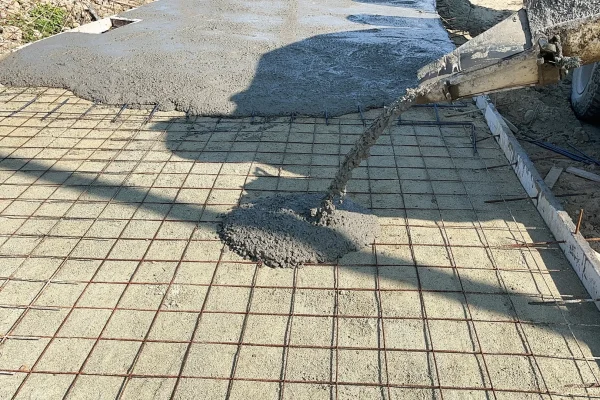 Fresh concrete slab being poured over rebar – Concrete Construction